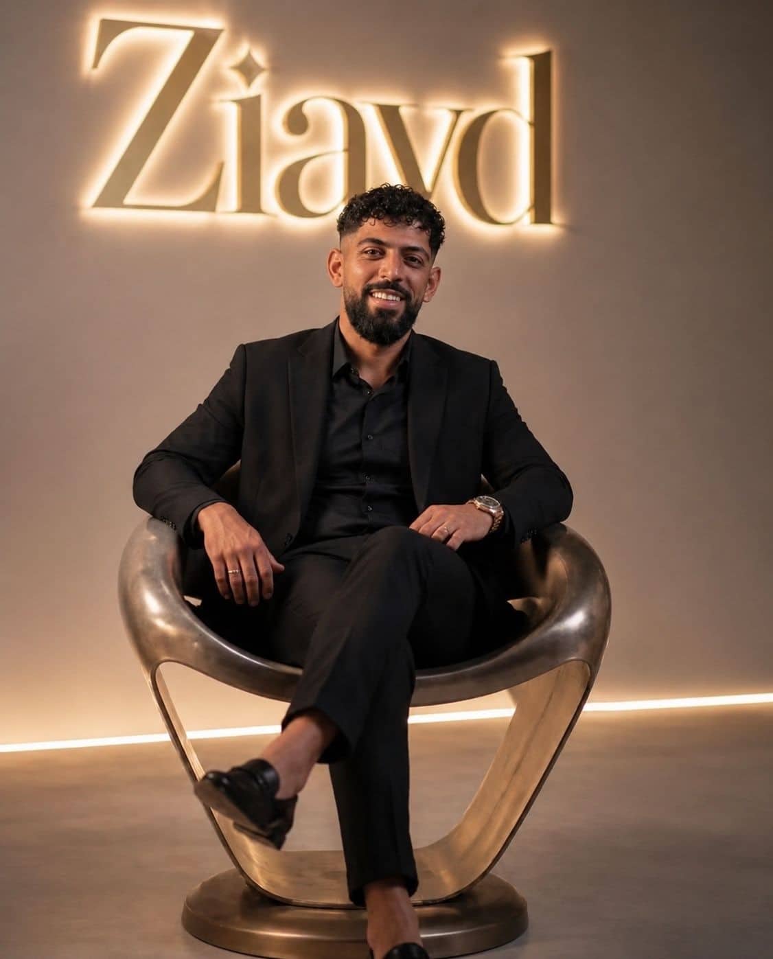 Ziayd, de kapper, zit in een stoel voor een verlicht naambord met zijn naam.